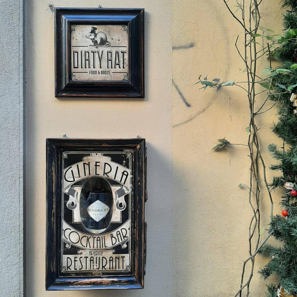 DECORI & INSEGNE Insegna con logo Dirty Rat affiancata da uno scrigno in legno e vetro con bottiglie di gin esposte