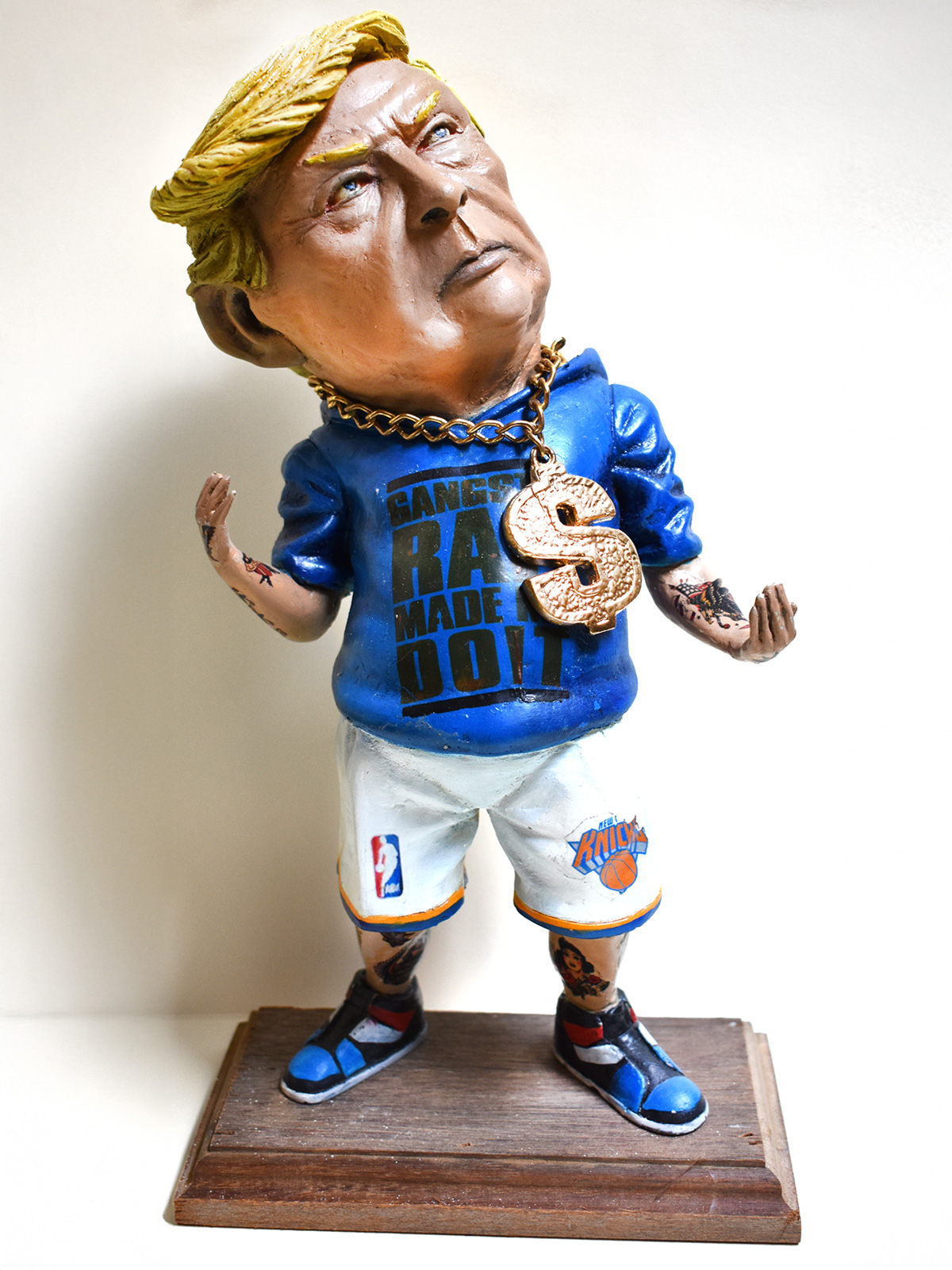 Scultura satirica artigianale di Donald Trump vestito da rapper con felpa “Gangsta Rap Made Me Do It” – complemento d’arredo creativo su misura ad Arezzo