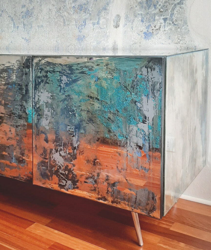 Grande madia moderna a quattro moduli con ante e cassetti rivestiti in specchio anticato, su pavimento in legno chiaro