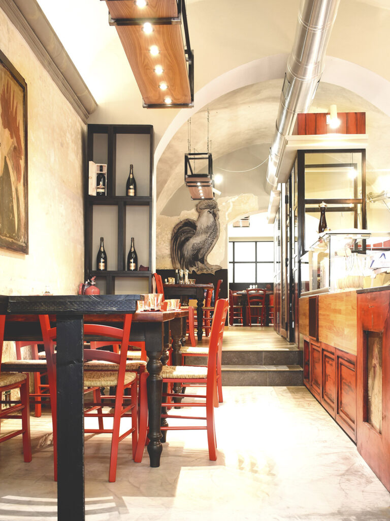 Vista del ristorante Oceria Francescana ad Arezzo con tavoli su misura, sedie rosse, bancone artigianale e divisorio cucina in ferro e vetro – arredamenti su misura per ristoranti