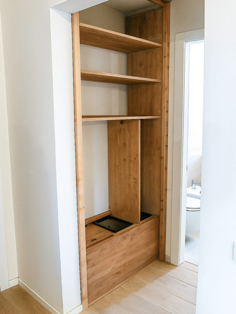 Armadio incassato in legno di noce tanganika con ante scorrevoli decorate a mano, botole inferiori per impianti e vano scopa, ripiani superiori per asciugamani e prodotti da bagno