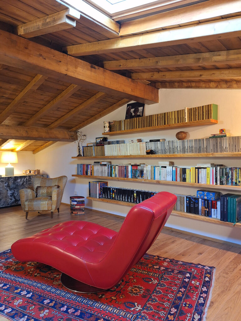 Libreria sospesa in legno di abete realizzata su misura in una soffitta, con mensole ancorate a muro in modo invisibile, design artigianale Bastanzetti Design