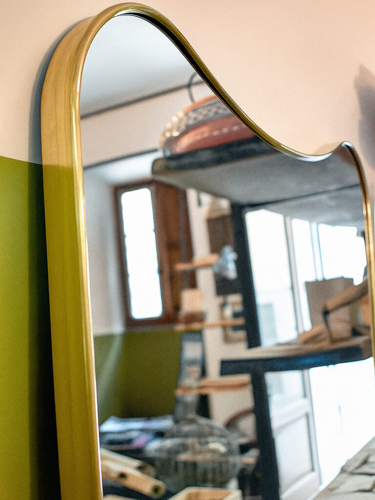 Specchio in ottone curvato a mano con cornice sinuosa anni ’70, arredamento su misura artigianale Bologna