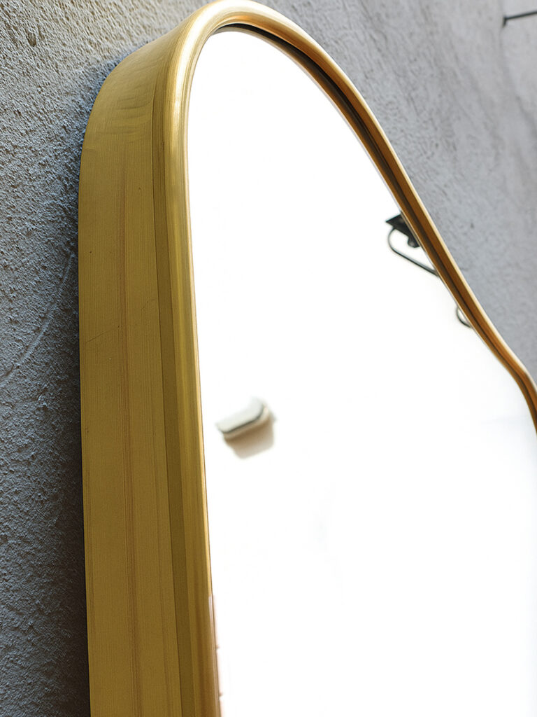 Specchio in ottone curvato a mano con cornice sinuosa anni ’70, arredamento su misura artigianale Bologna